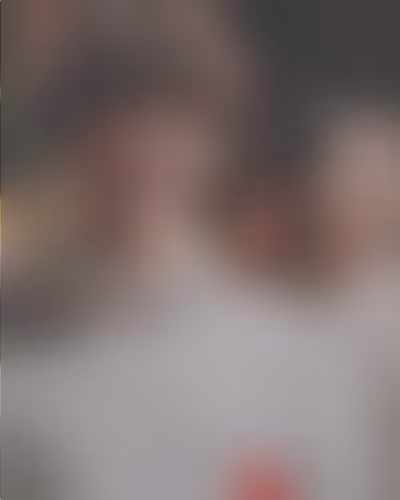 Unscharfes Bild einer Person in einem weißen Oberteil vor einem dunklen Hintergrund.