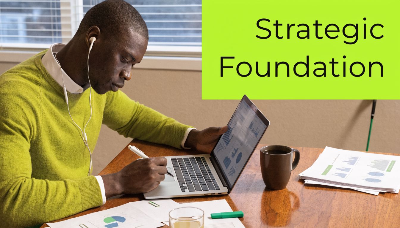 A professional man with headphones sitting at a desk and working on a laptop near business charts.