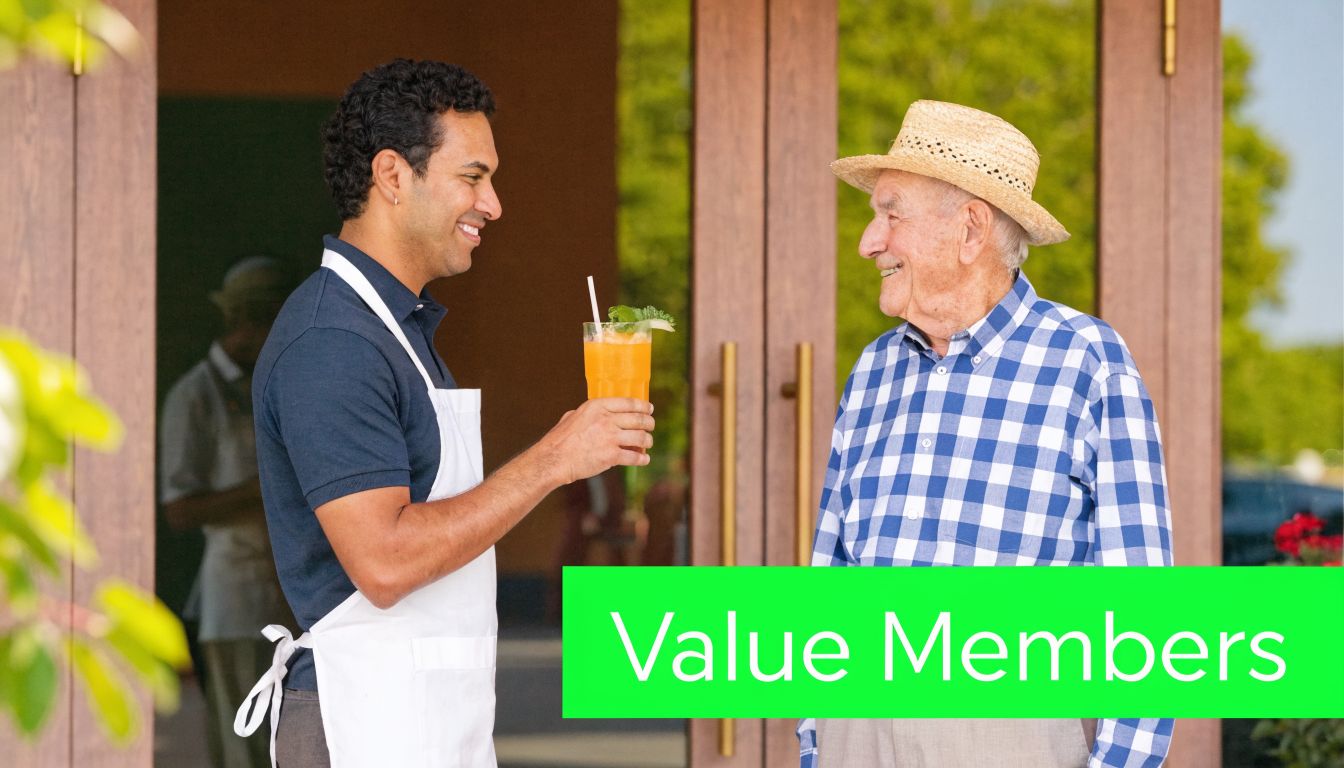 A friendly waiter offering a refreshing orange beverage to an elderly man wearing a straw hat.