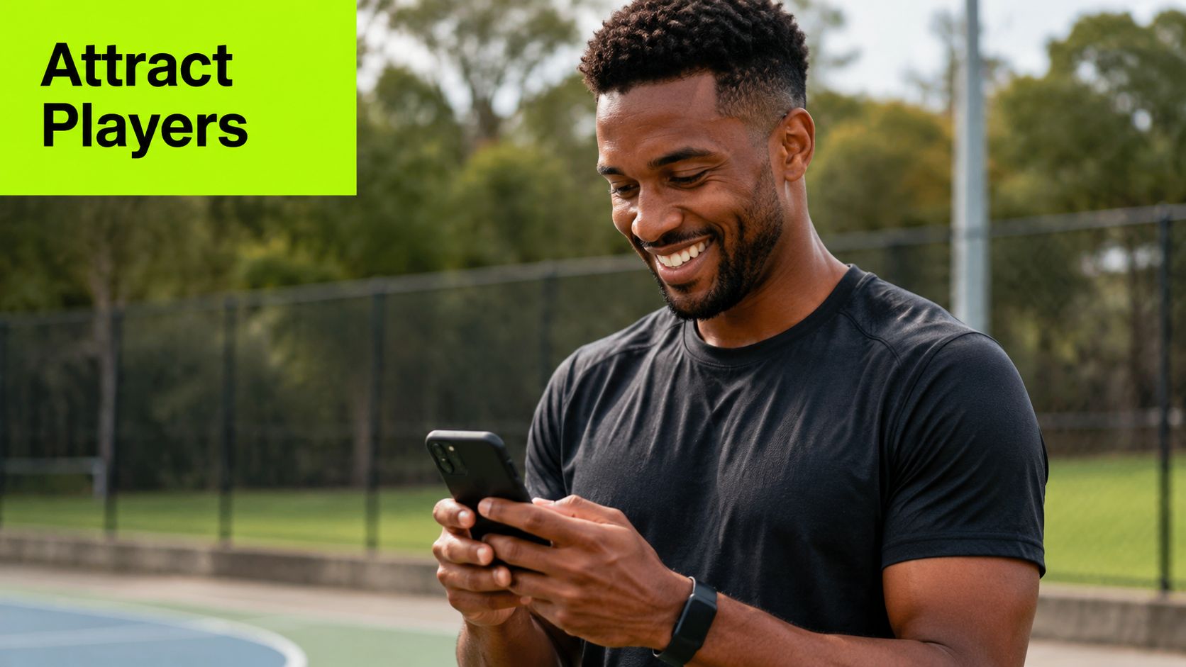 An athletic man standing on a sports court smiling while using his smartphone to check notifications.