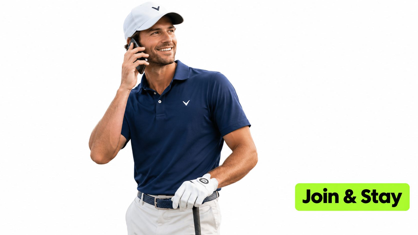 A golfer wearing a navy blue polo shirt and white cap speaks on his smartphone outdoors.