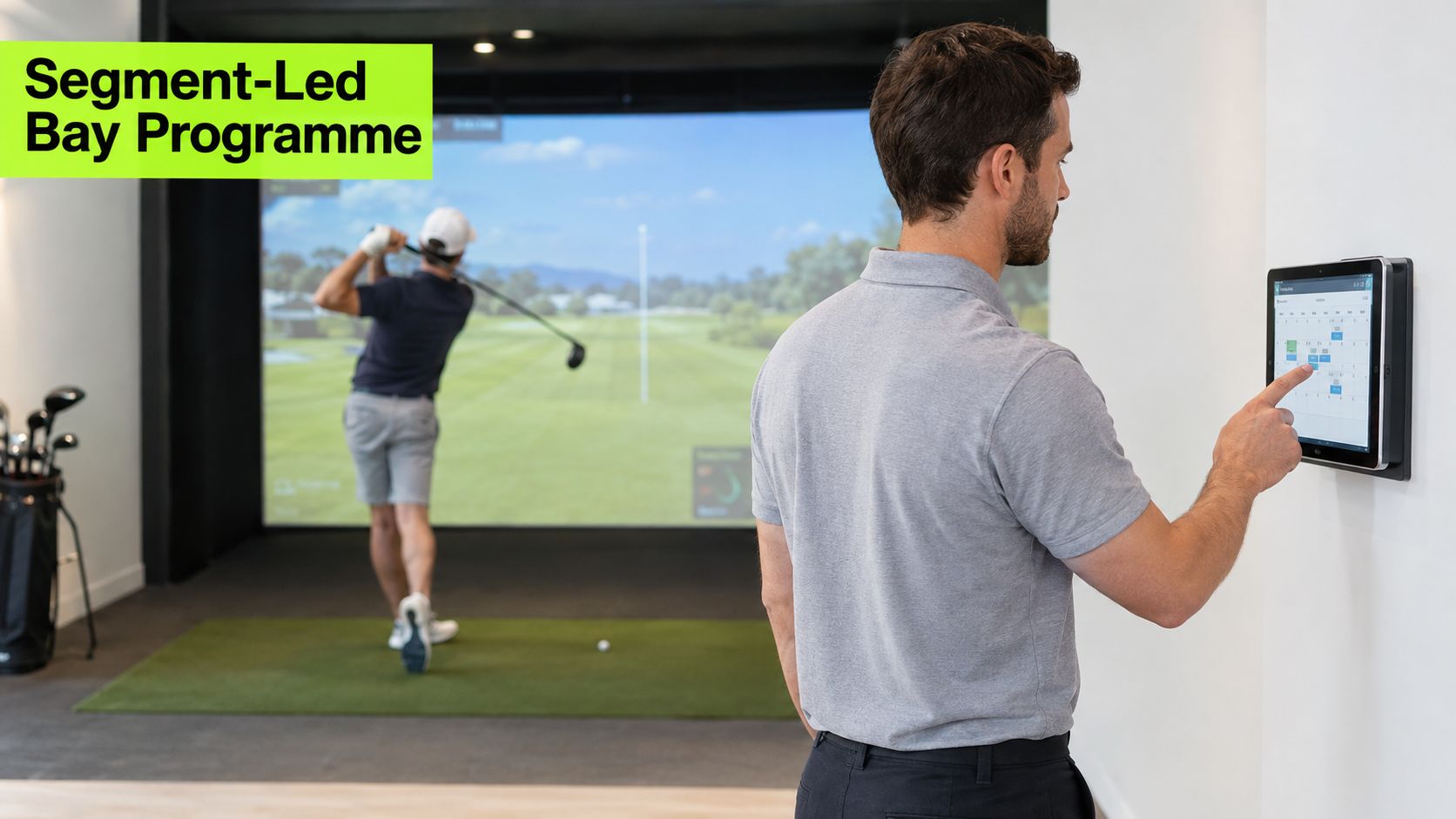 A man in a polo shirt uses a digital tablet to manage a golf simulator bay booking.