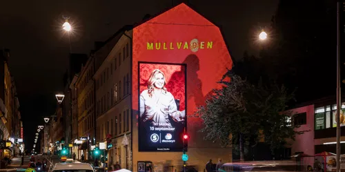 A digital screen and a projection work together to create an advert on the wall.