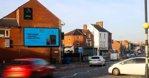 a digital billboard located on a busy street surrounded by shops and residential buildings