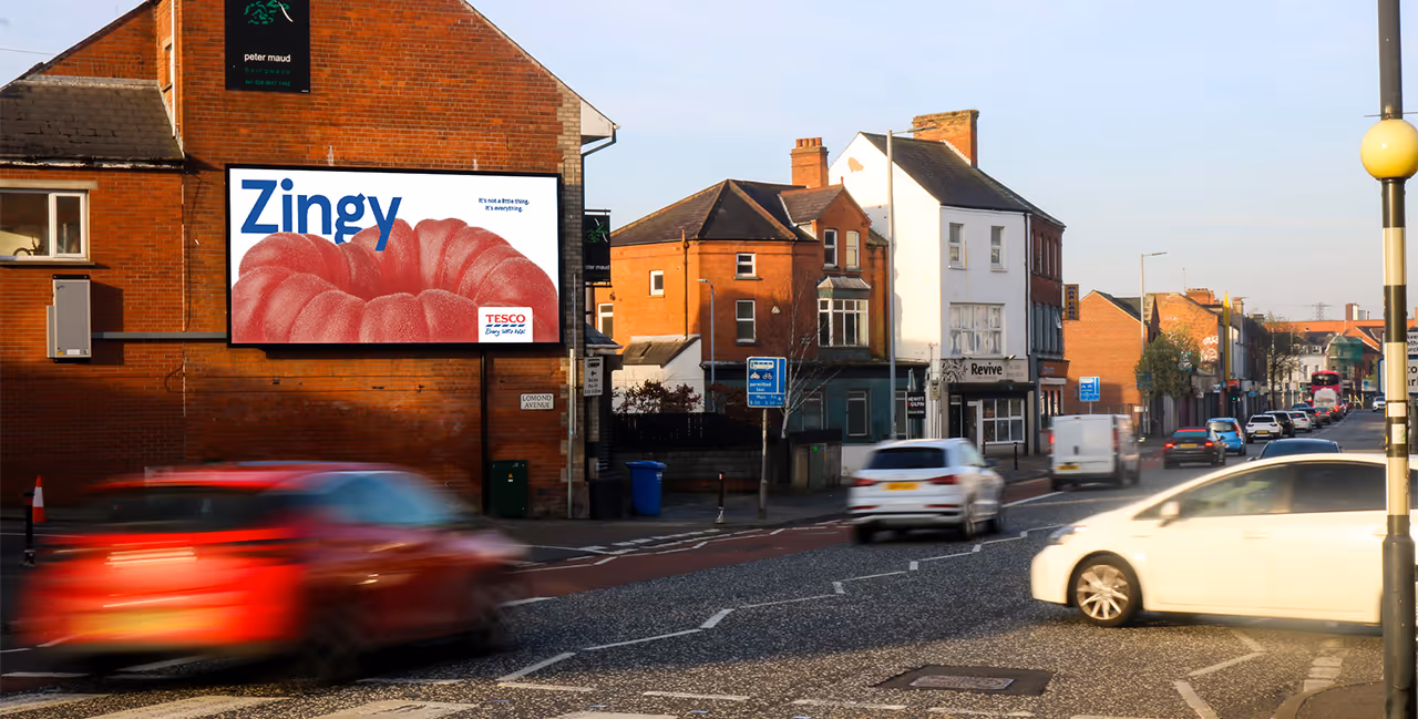 A large digital billboard advertisement on a busy street surrounded by shops and residential buildings