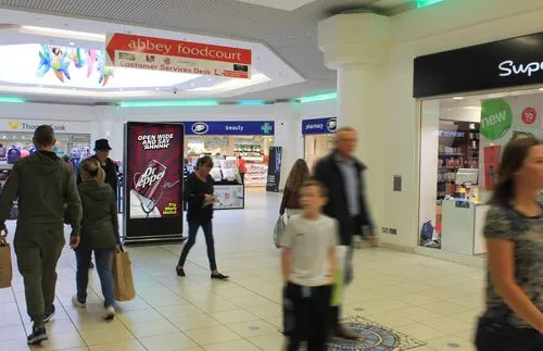 Digital advertisement inside a shopping centre with shoppers walking past