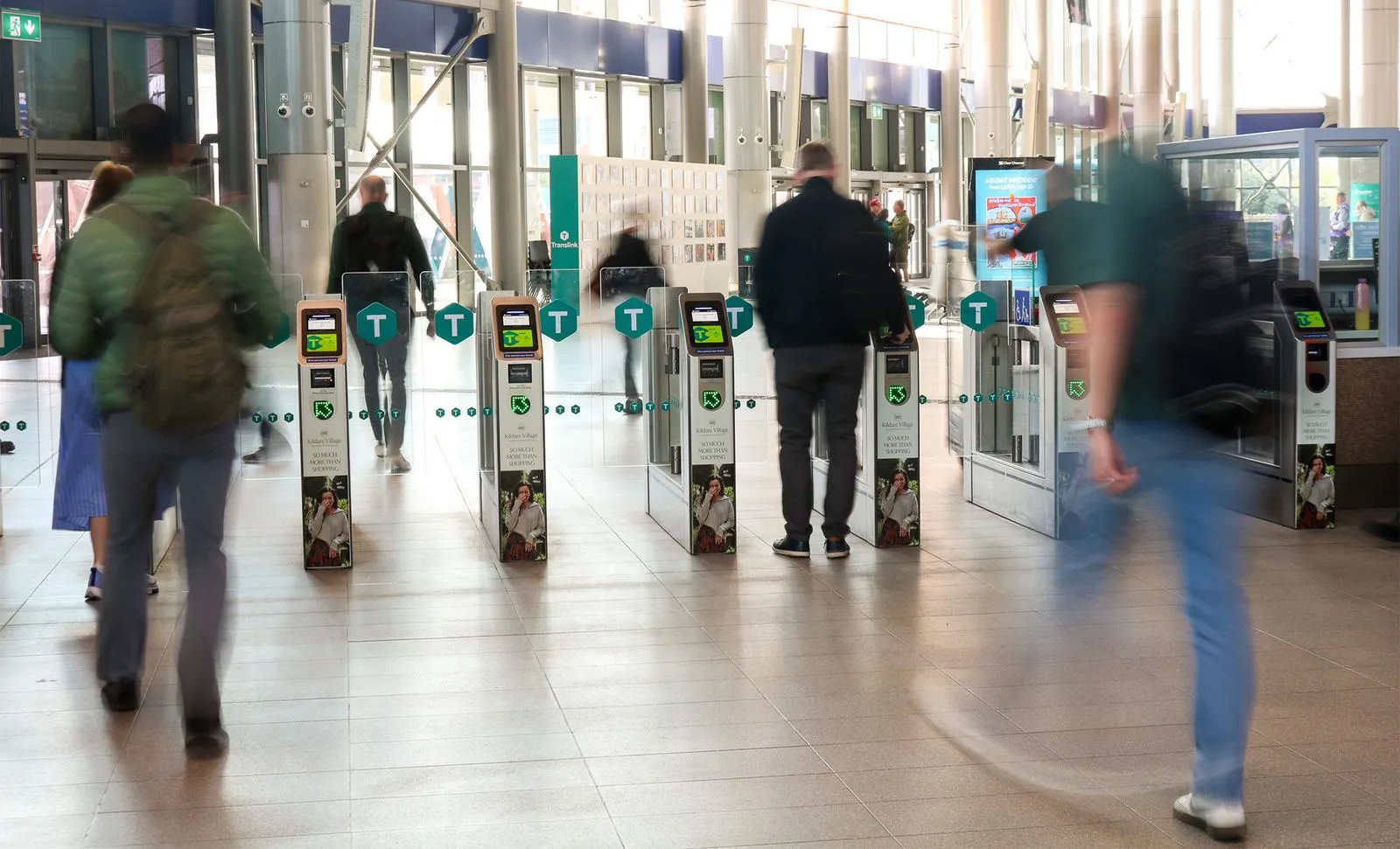 Branded train station turnstiles in a busy train station with people walking throughpeople 
