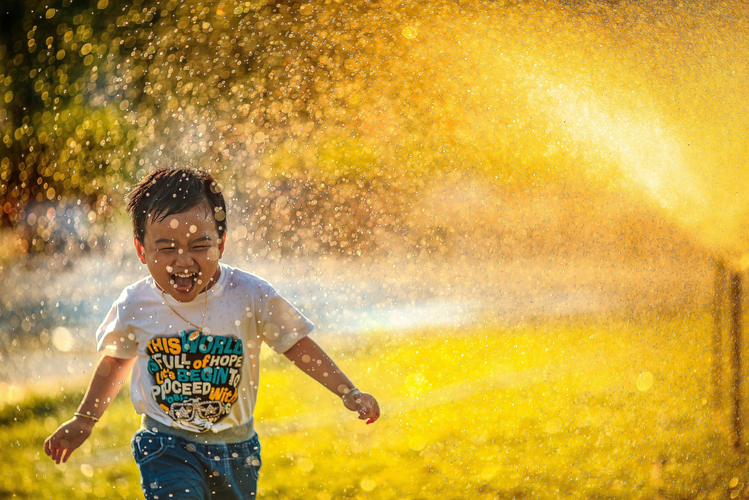 Happy child running through a sprinkler.