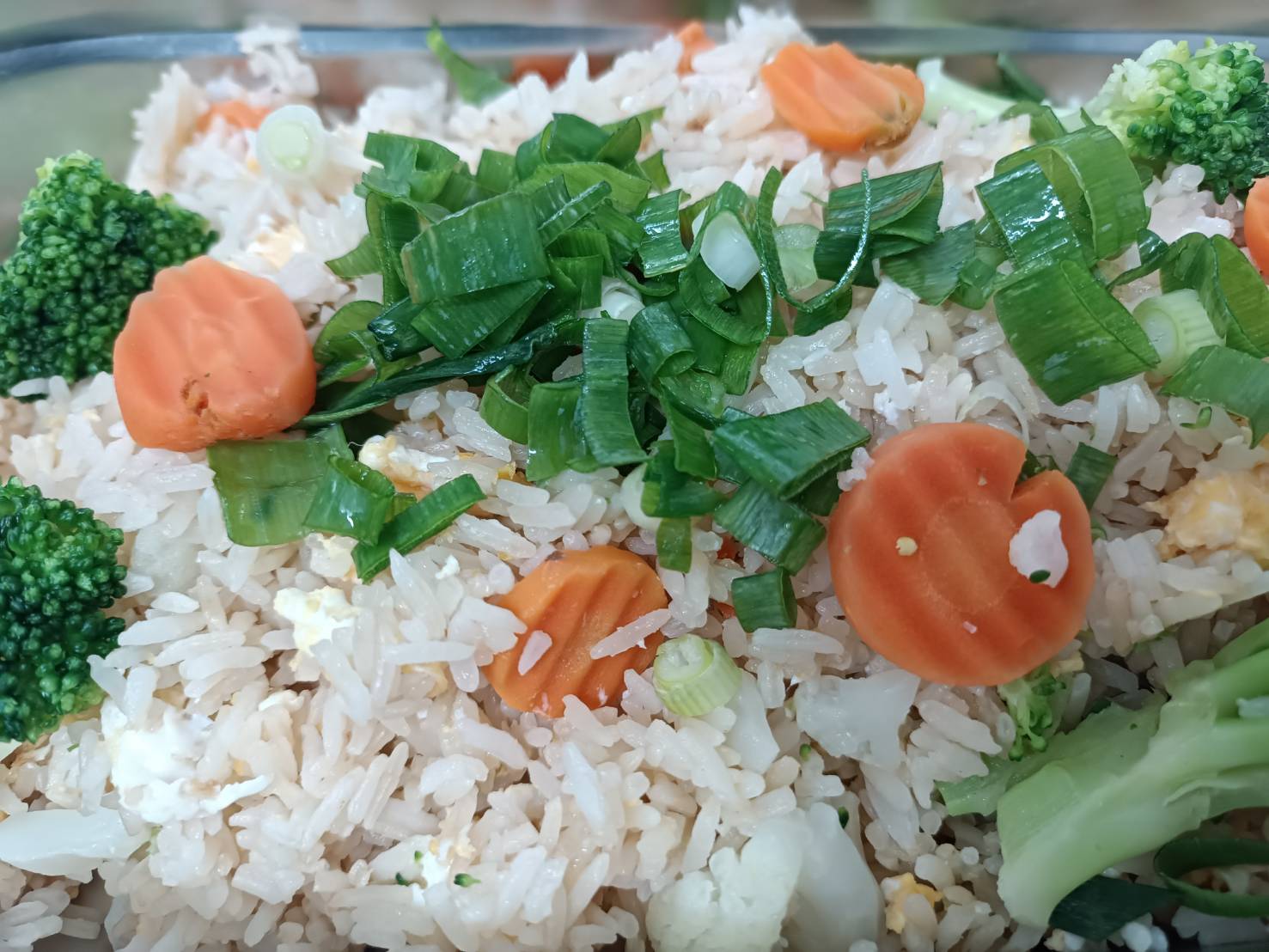 Nahaufnahme eines Gemüsereis mit Karotten, Brokkoli, Frühlingszwiebeln und Blumenkohl.