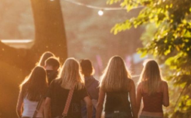 Group of friends walking through festival campsite