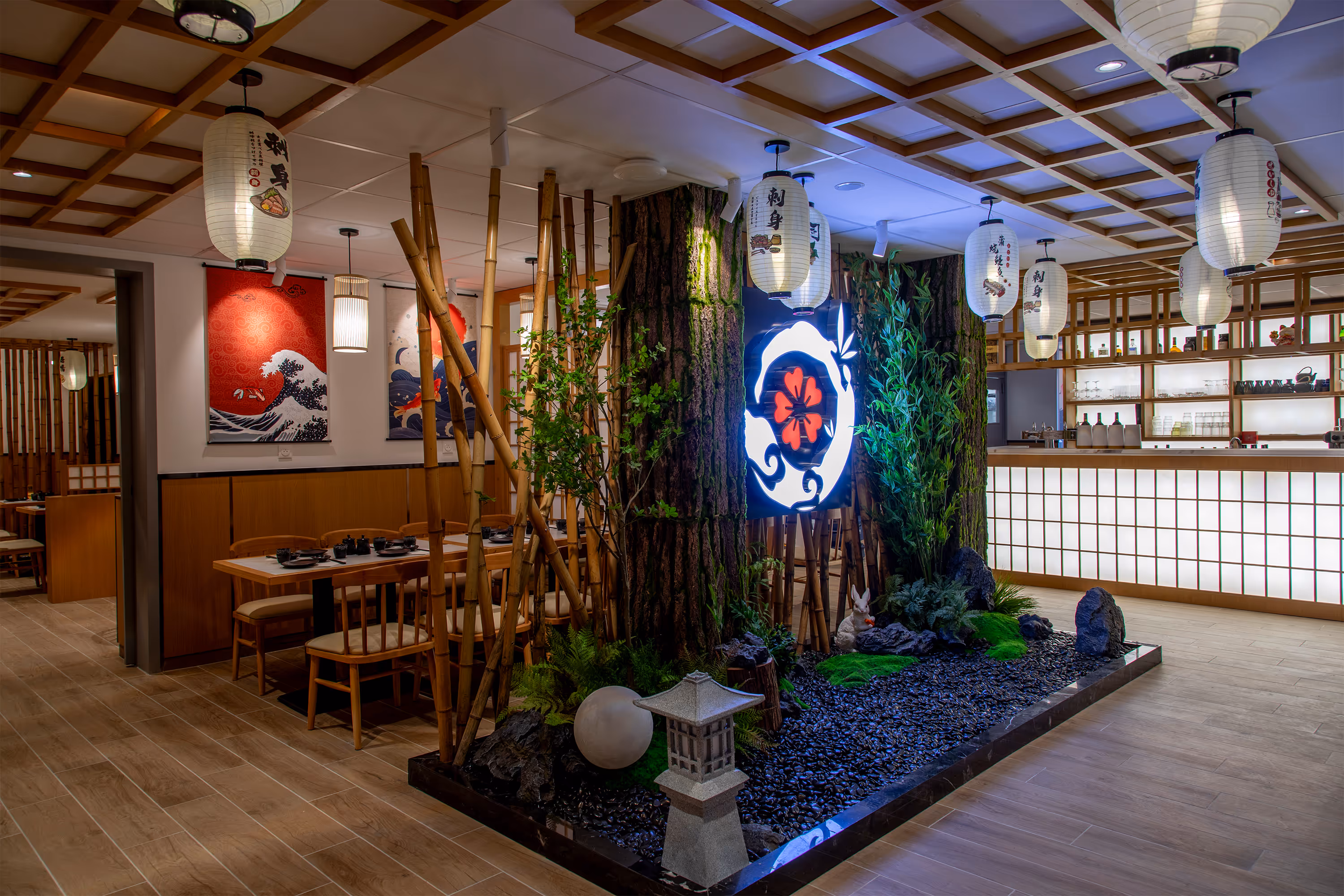 Intérieur moderne d'un restaurant japonais avec jardin zen central, lanternes suspendues et comptoir éclairé.