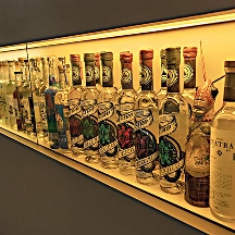 Shelf displaying a variety of bottled alcoholic beverages with illuminated backlighting.