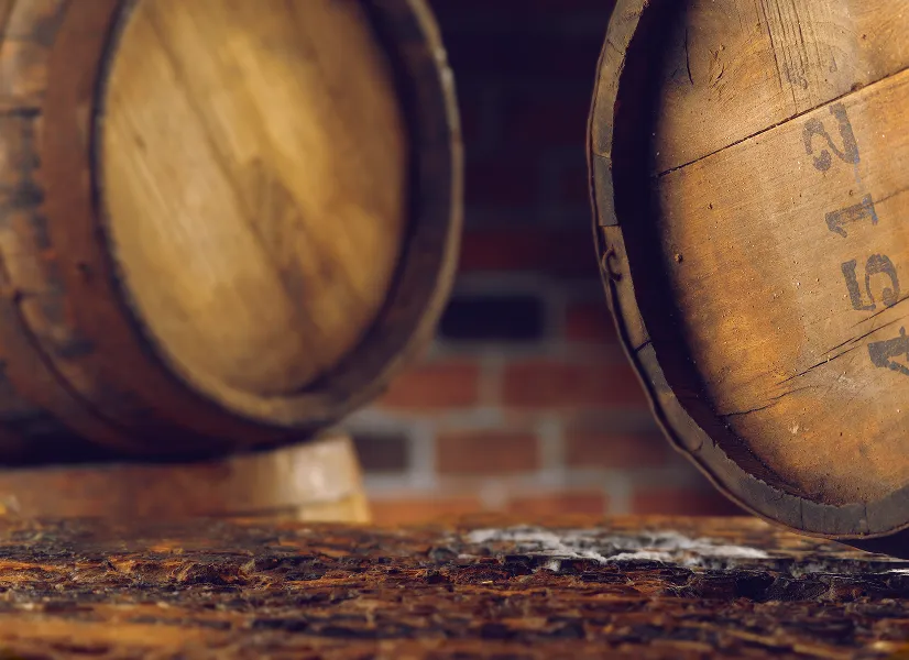 Close-up of wooden barrels on a rough surface with a blurred brick wall background.