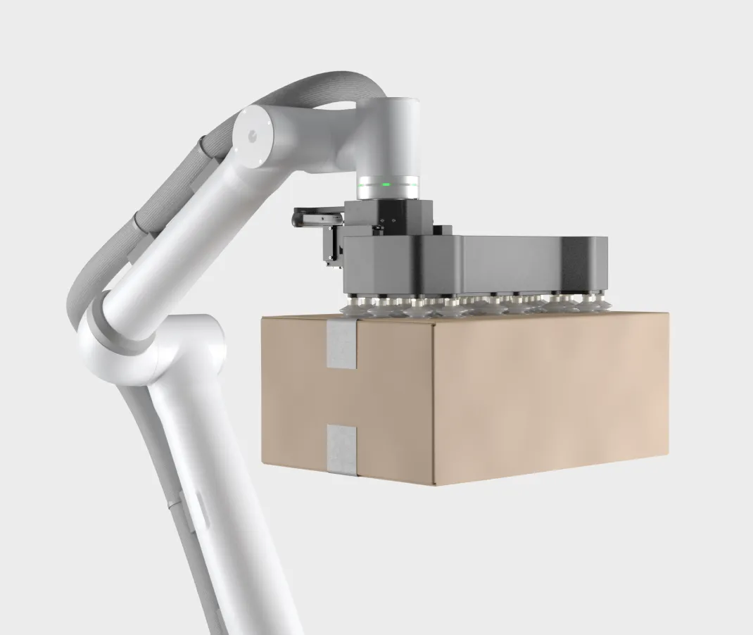 Robotic arm lifting a cardboard box using a vacuum gripper with multiple suction cups.