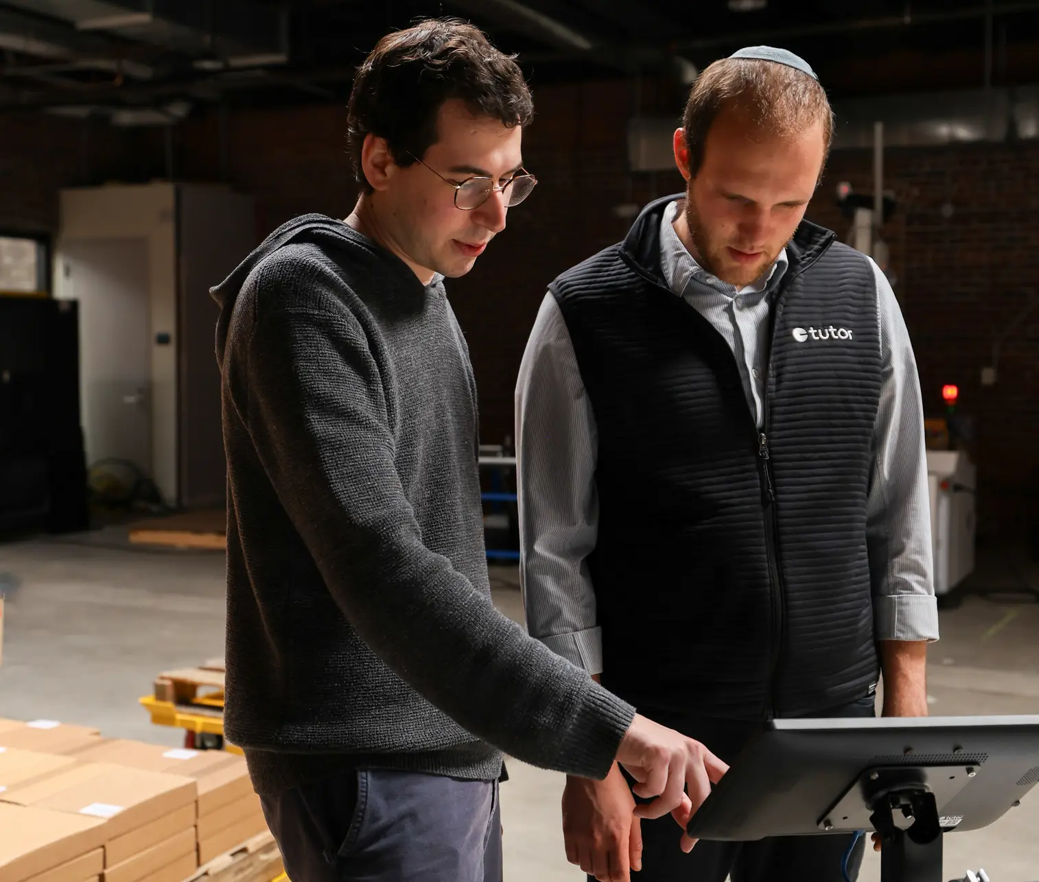 Two people stand at Cassie's HMI, the control tablet designed for use by line workers and operators.