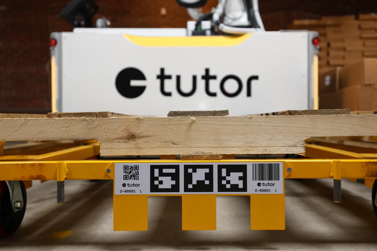 A Tutor dolly holding a pallet, docked to a Tutor Cassie robot visible behind it.
