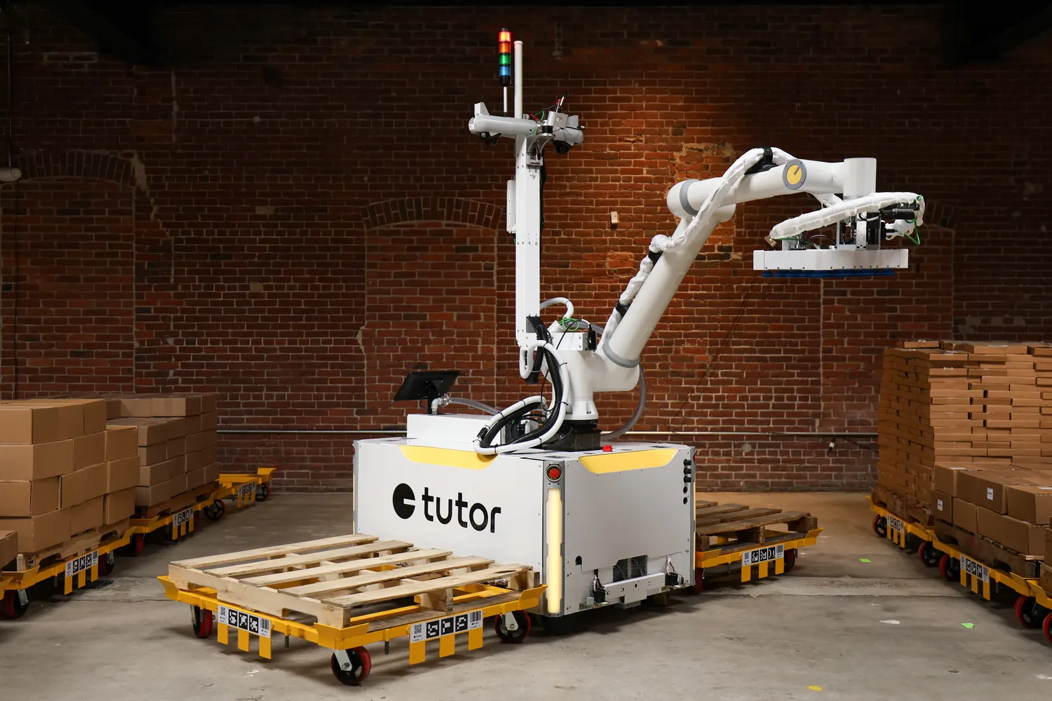 Tutor's mobile autonomous warehouse robot, Cassie, in a warehouse aisle of pallets.
