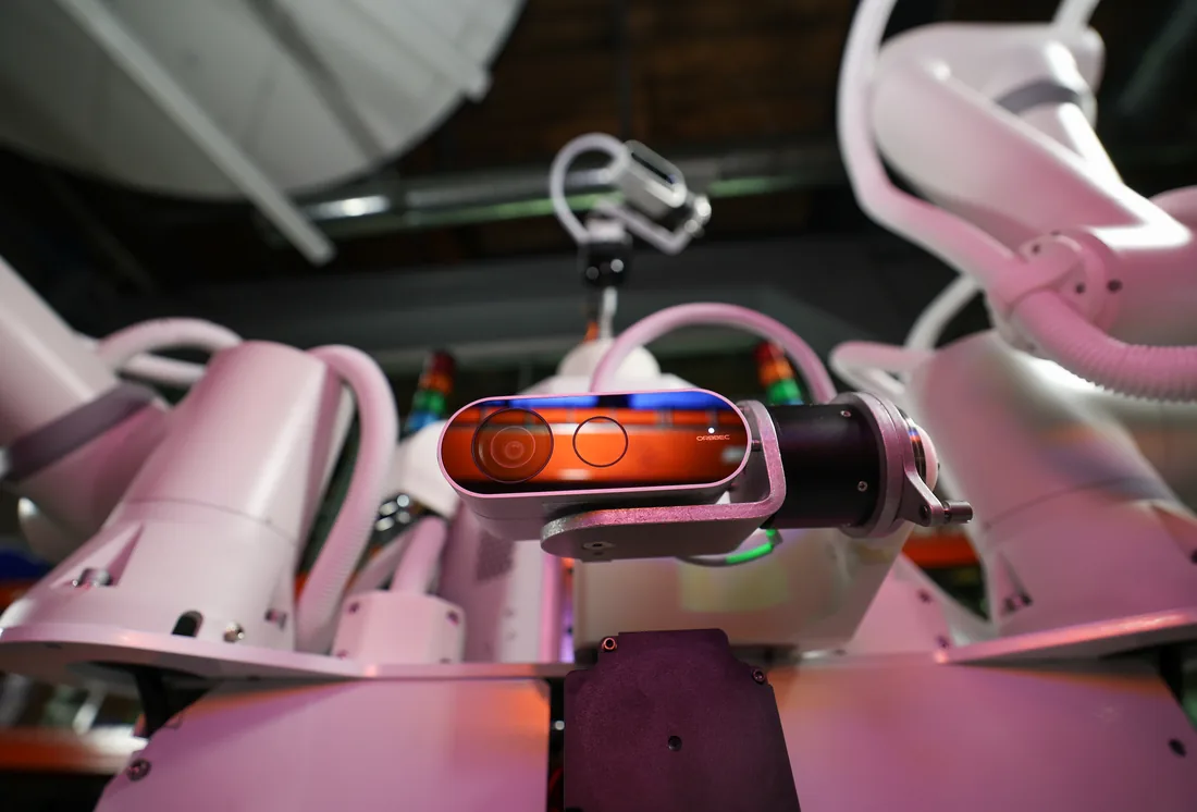 Close-up of the depth camera mounted on Tutor robot Sonny's torso, lit in pink and orange.