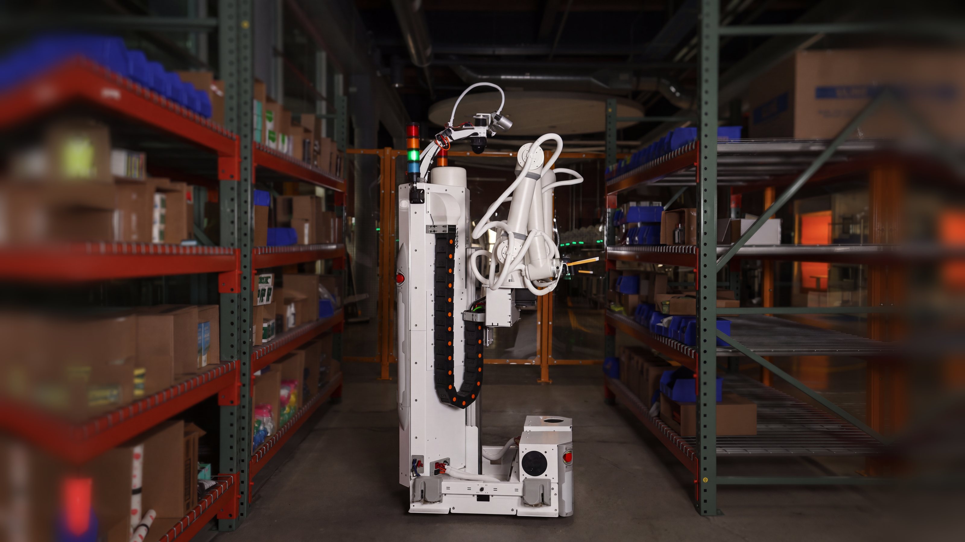Sonny, Tutor's two-armed mobile robot worker, standing in a warehouse aisle between shelves.