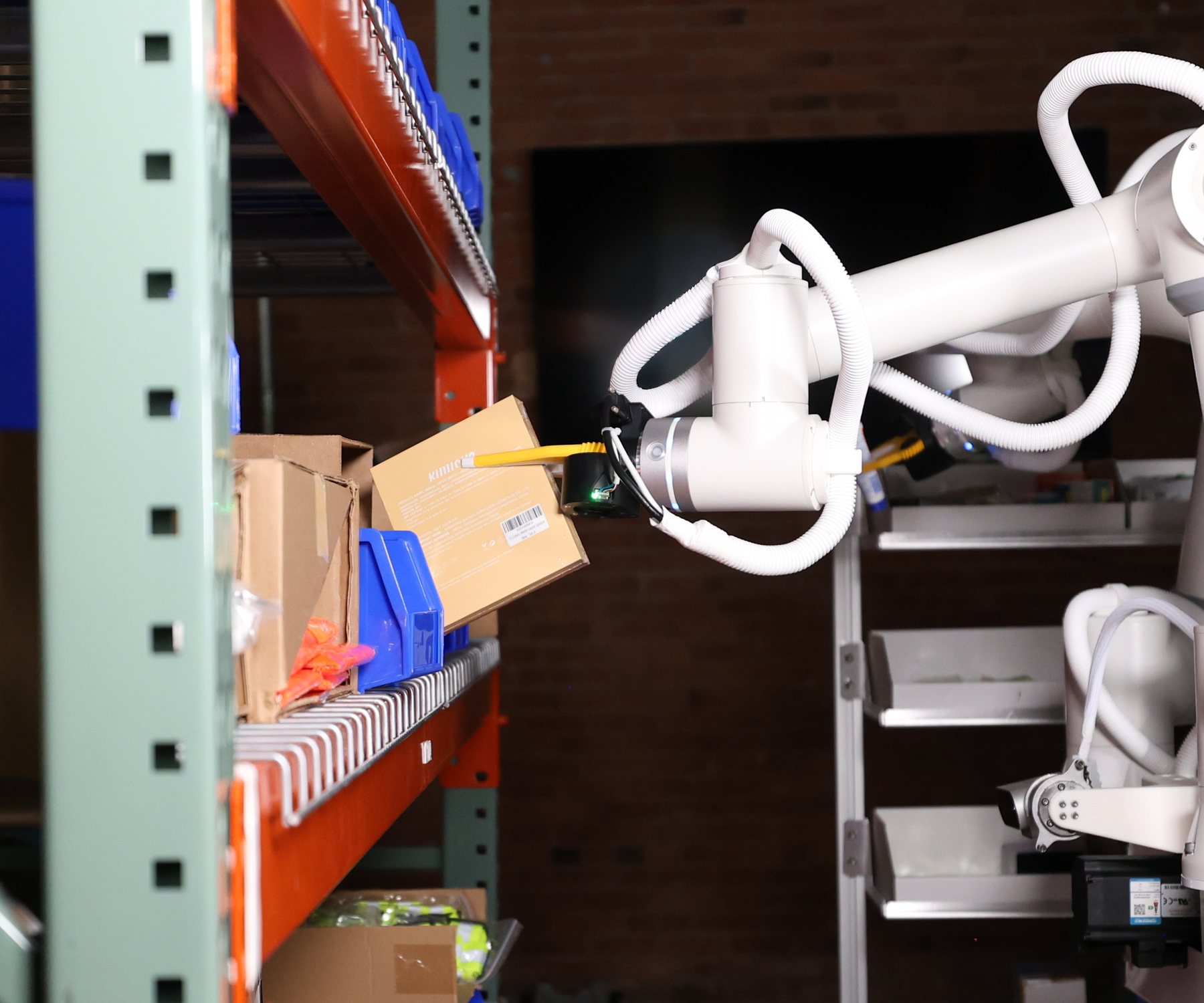 Sonny's gripper picking a small box from a warehouse shelf.