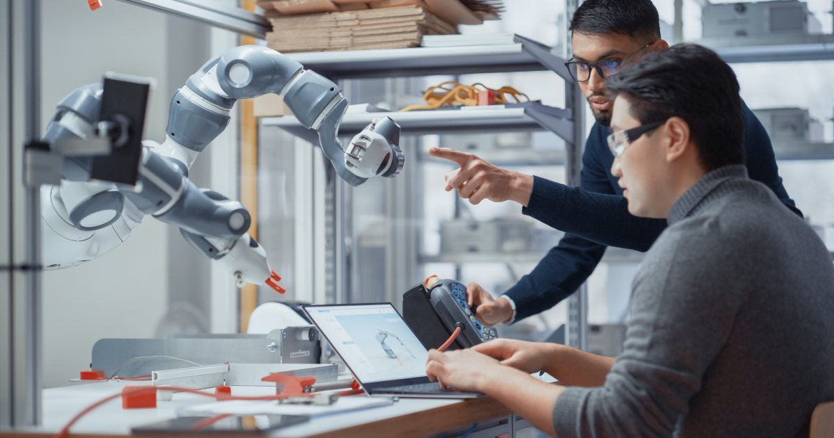 engineers programming and testing a robotic arm in a lab setting