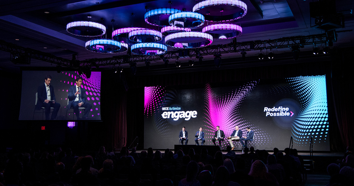 panel discussion on a stage with colorful LED backdrop and audience seated in front