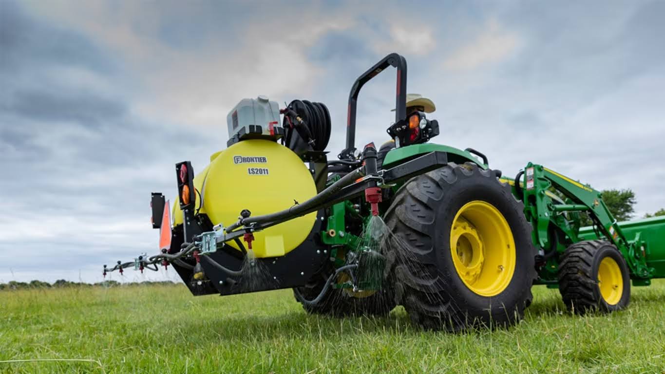 John Deere compact utility tractor with a liquid sprayer attached.