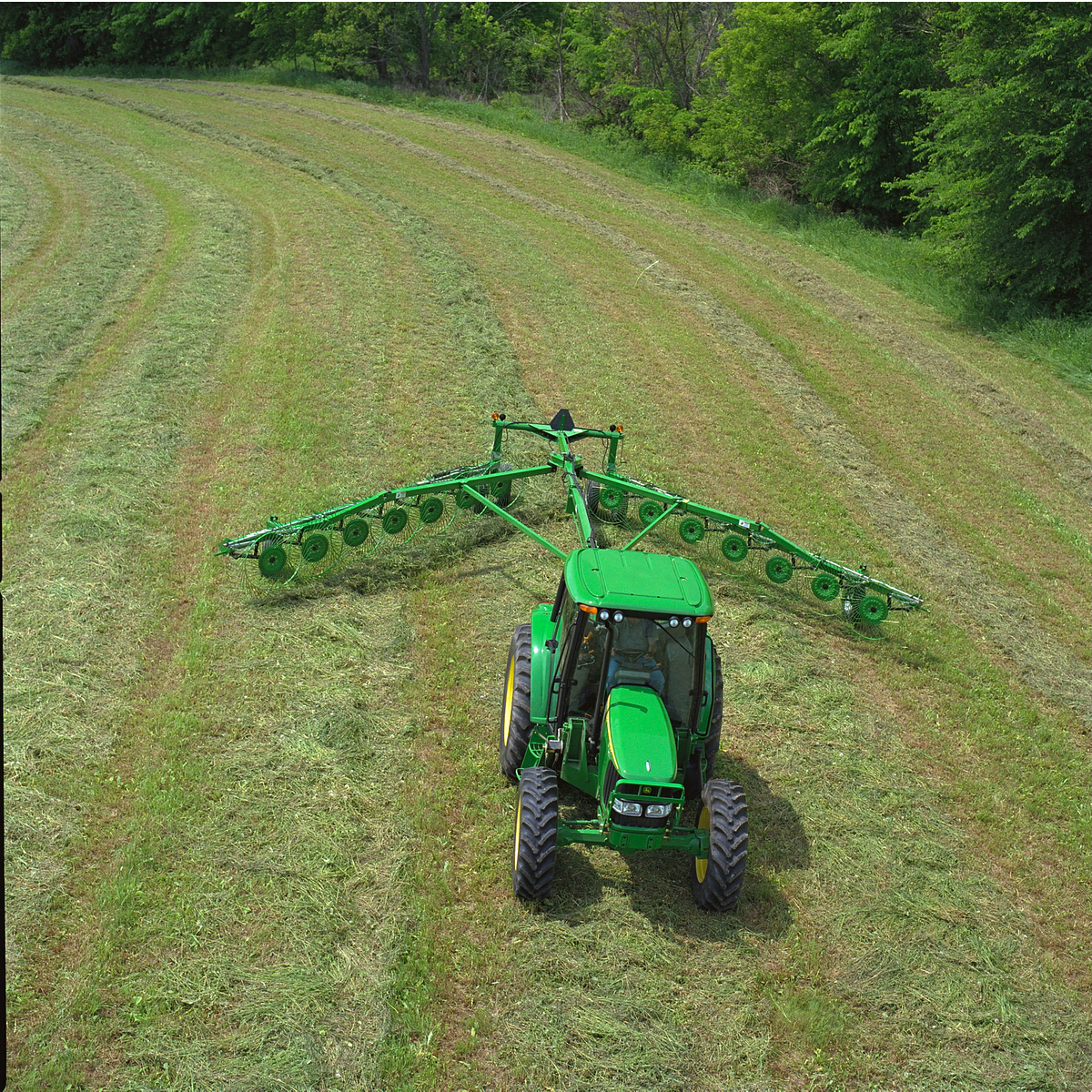 Top view of a green tractor pulling a WR1214 High-Capacity Wheel Rake across a grass field
