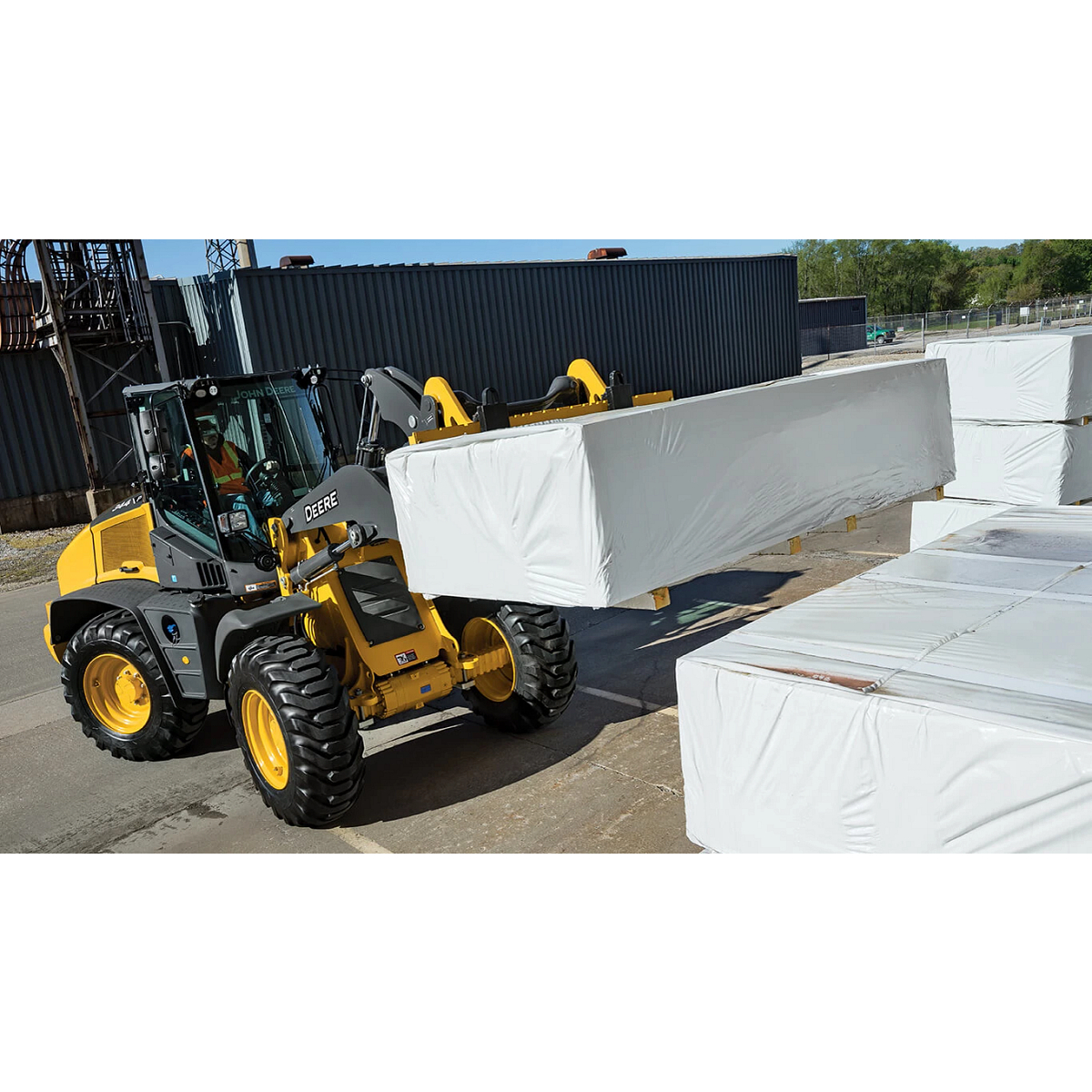 344 P-Tier wheel loader moving pallets with fork attachments.