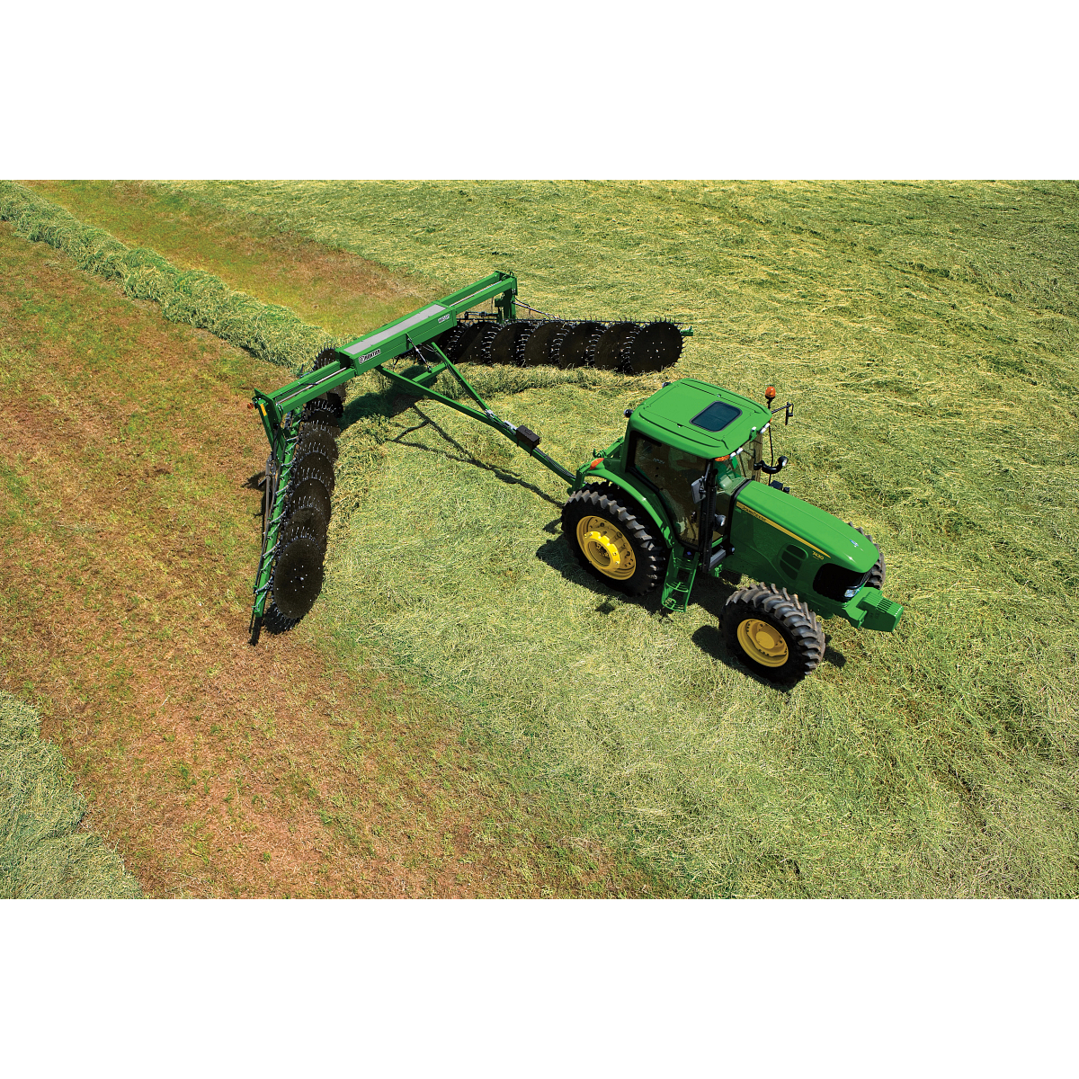 Top right view of a green tractor pulling a WR5417 wheel rake across a green hay field
