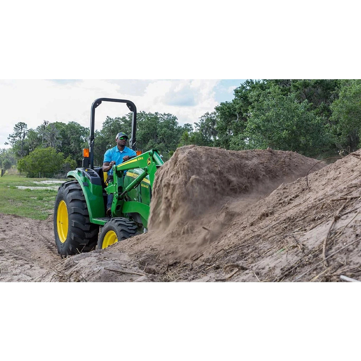 farmer operating a 4044M Compact Tractor to move dirt