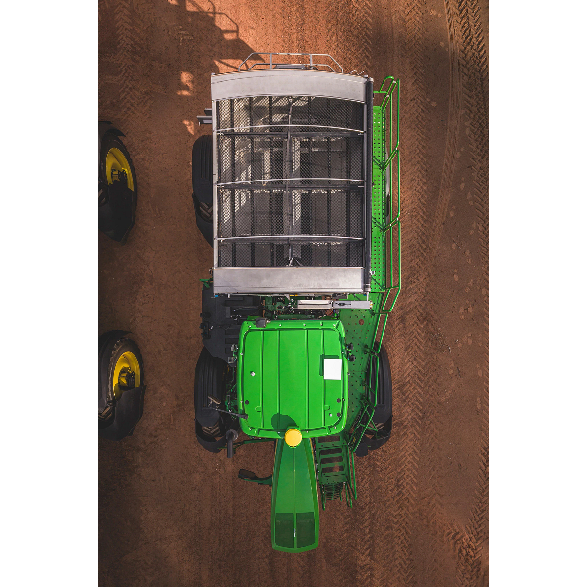 Top-down aerial view of a John Deere machine parked on a dirt surface, showing a roof-mounted JDLink Boost Mini Terminal