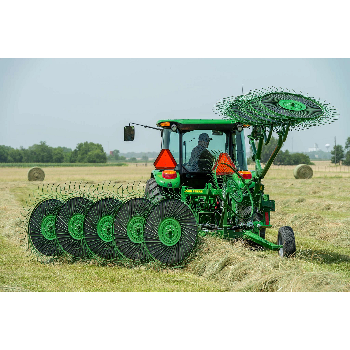 Rear view of a WR00 wheel rake at work behind a tractor in a hay field