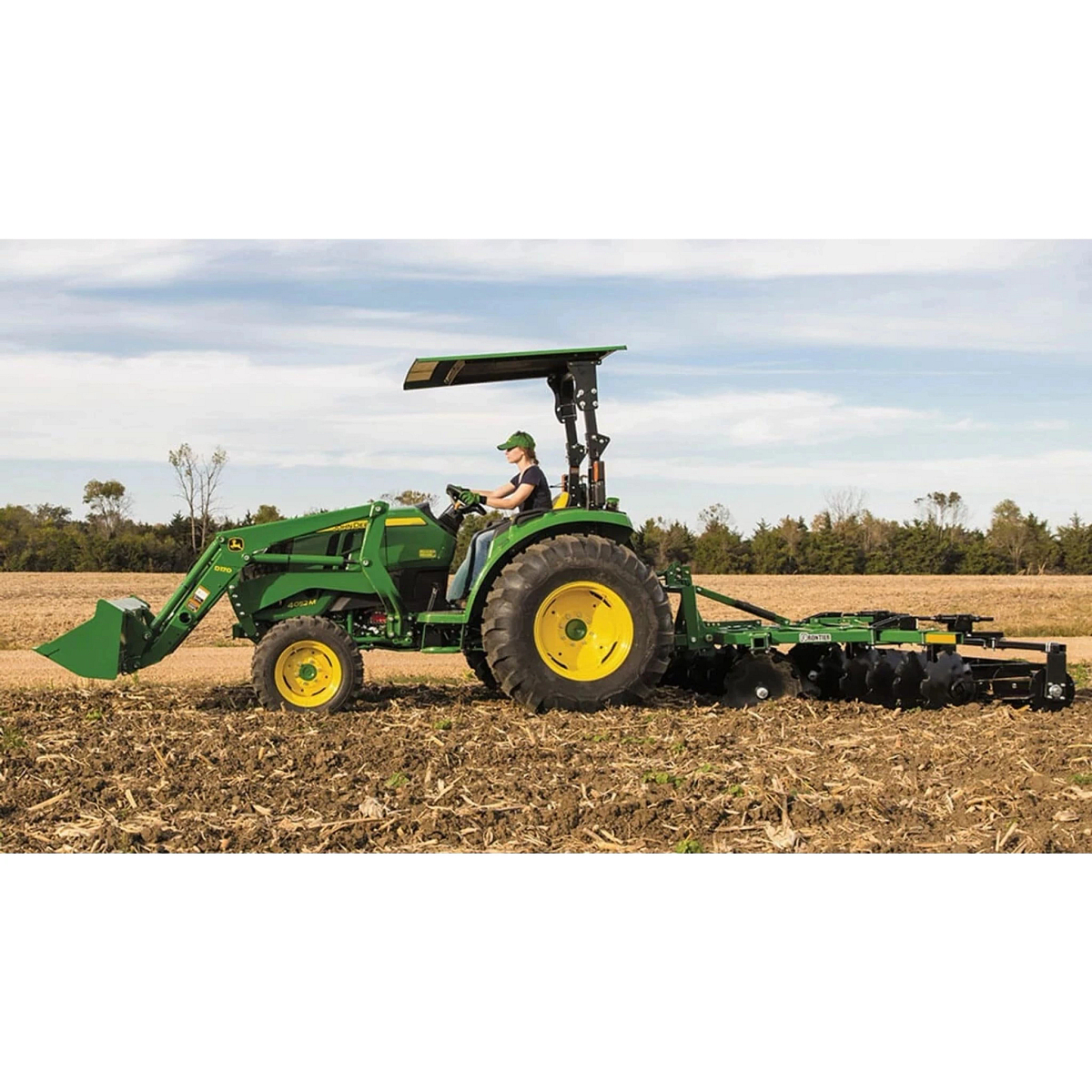 farmer tilling a corn field using a 4052M Compact Tractor with a tillage attachment
