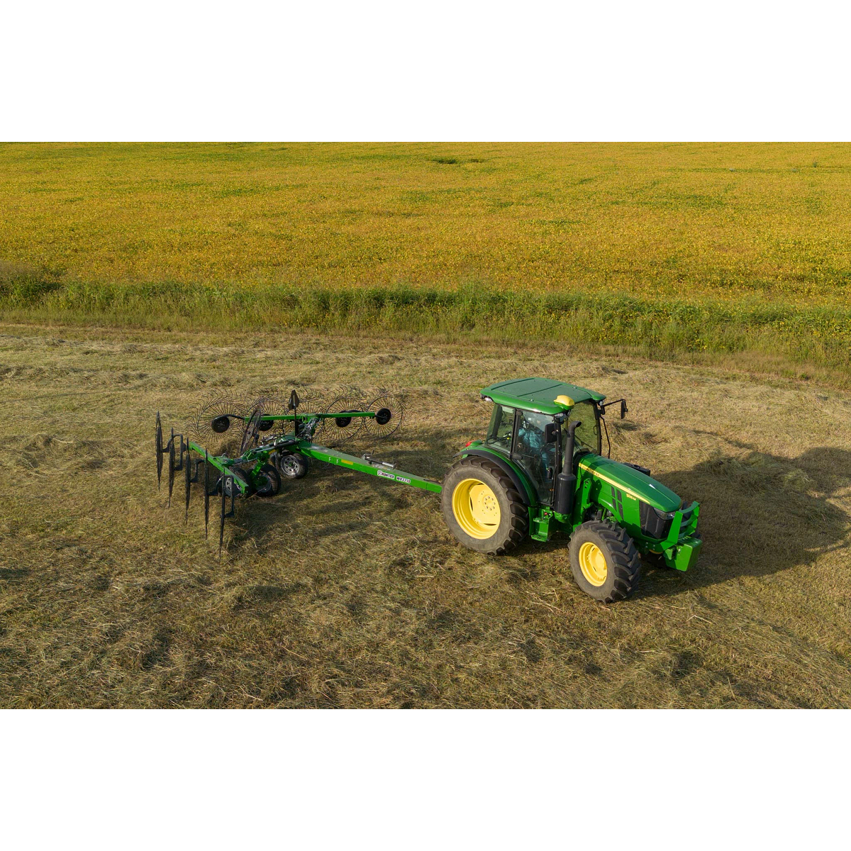 Top right view of a 5125M tractor pulling a WR3210 wheel rake across a swatch of felled hay