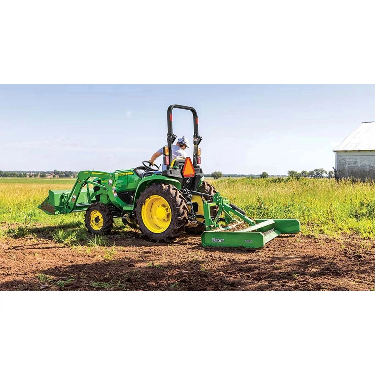 3025E 3 Series Compact Tractors with a farmer is driving a tractor with a plow attachment