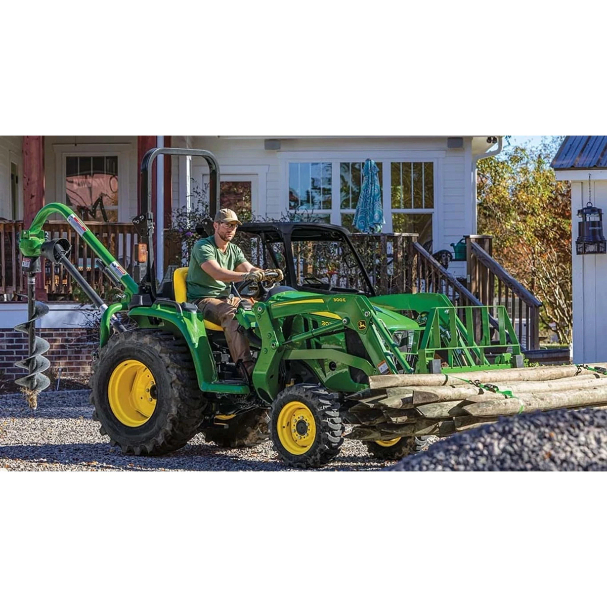 3025E 3 Series Compact Tractors with a farmer driving a tractor with a log loader attached to it