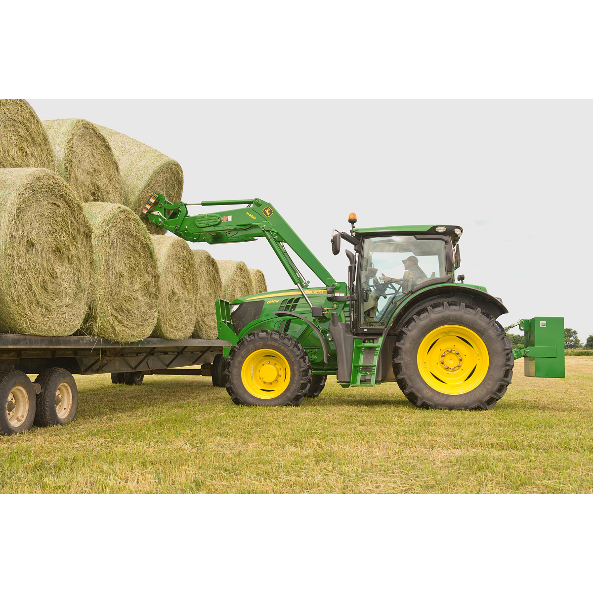 6140R Tractor with AB12G Bale Spear loading round bale onto a flatbed