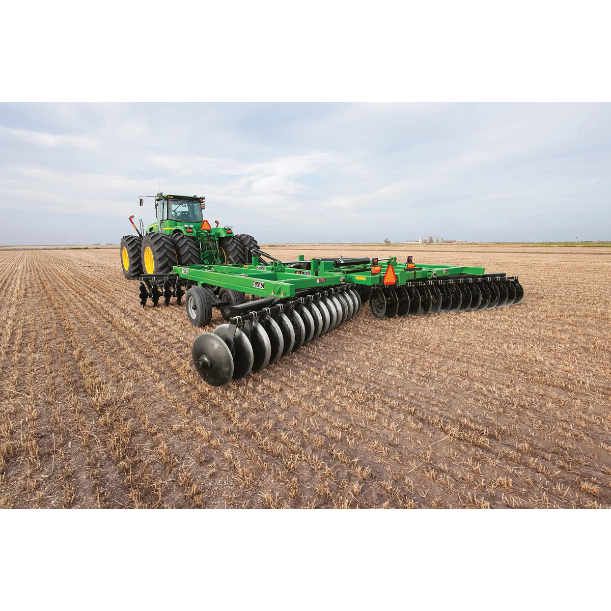 Left rear view of a tractor pulling a Frontier Tandem 51 Series Disk Harrow in the field