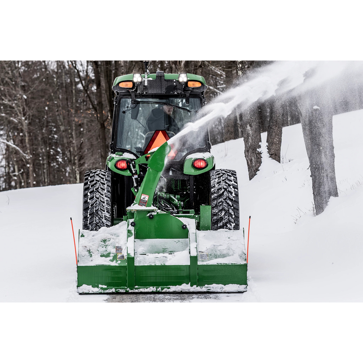 Blowing snow using a SB1174 Snowblower on 4075R Tractor along a tree line