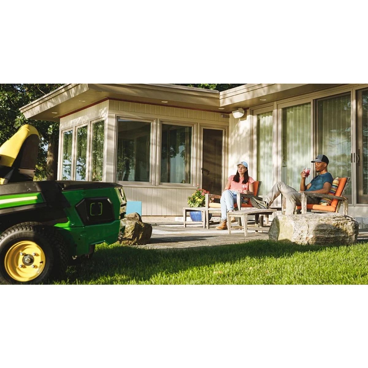 Two homeowners sitting on a patio with drinks with a utility vehicle in the foreground