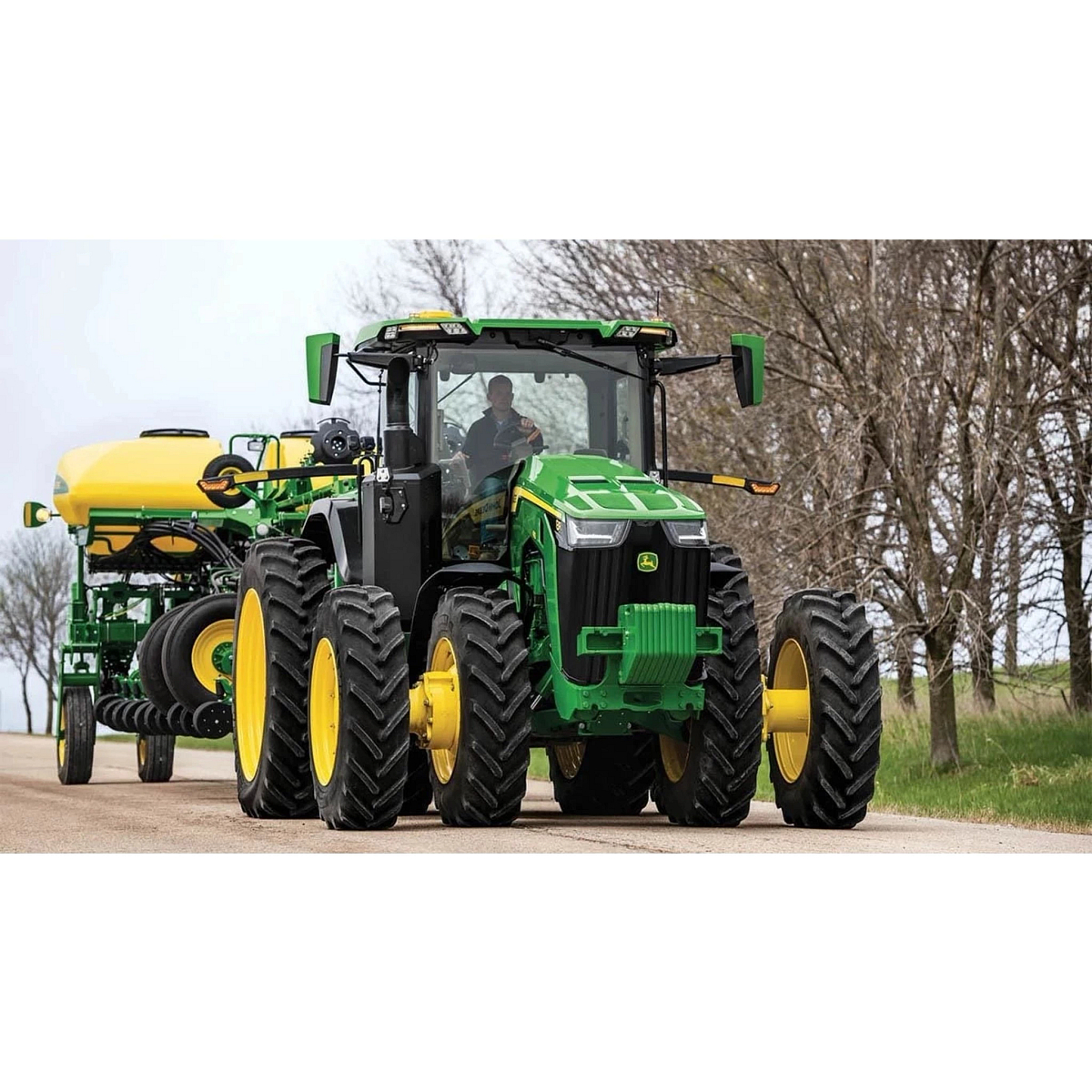 8R 340 Tractor being driven on a gravel road with a sprayer attachment