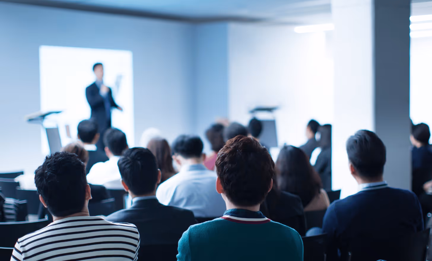 Groupe de personnes assises assistant à une présentation en salle de conférence.