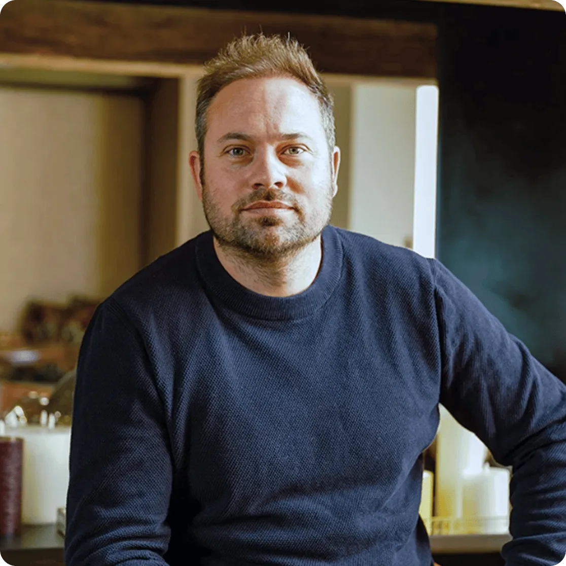 Nathan Pissarro wearing a dark blue sweater sitting indoors, looking at the camera.