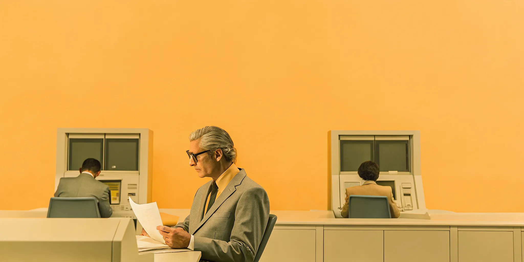 Senior program director reviewing contract documentation and schedule reports in an aerospace program office