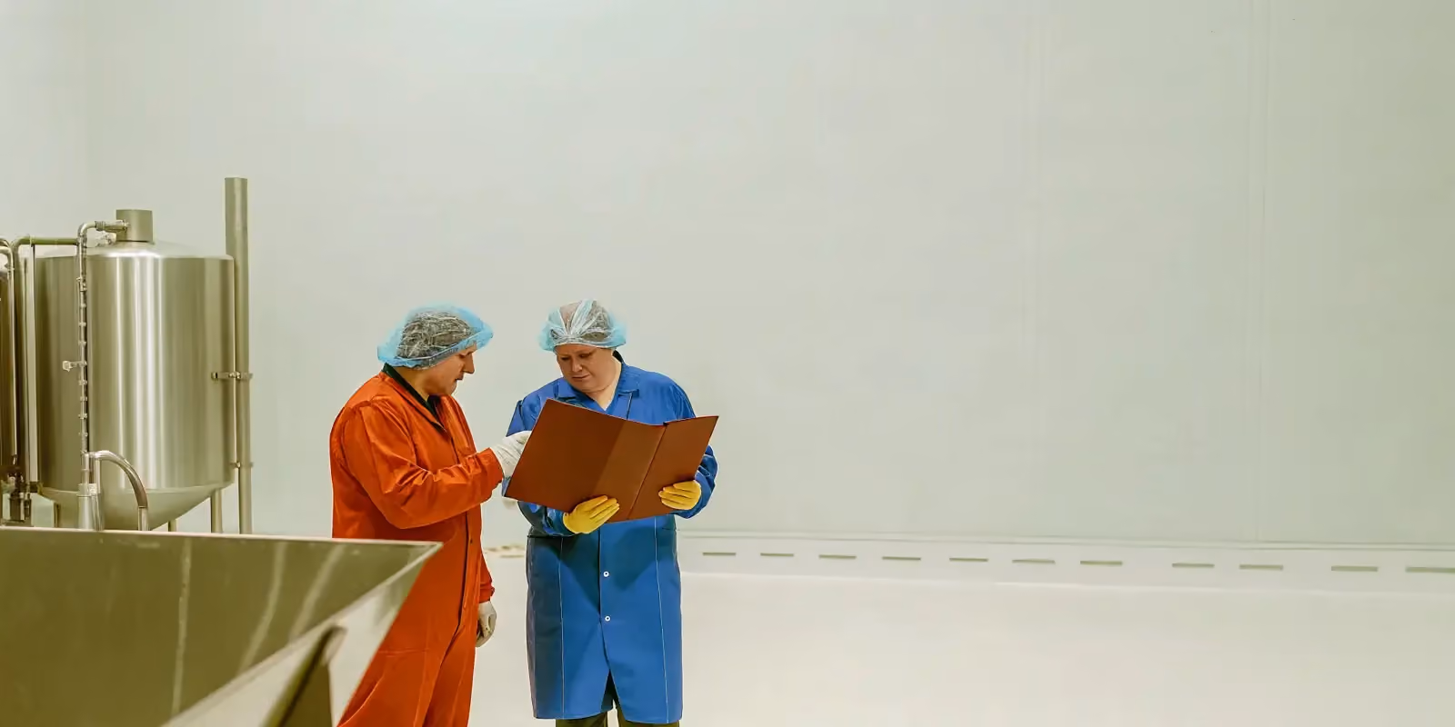 Food manufacturing facility quality assurance team reviewing production documents on the plant floor