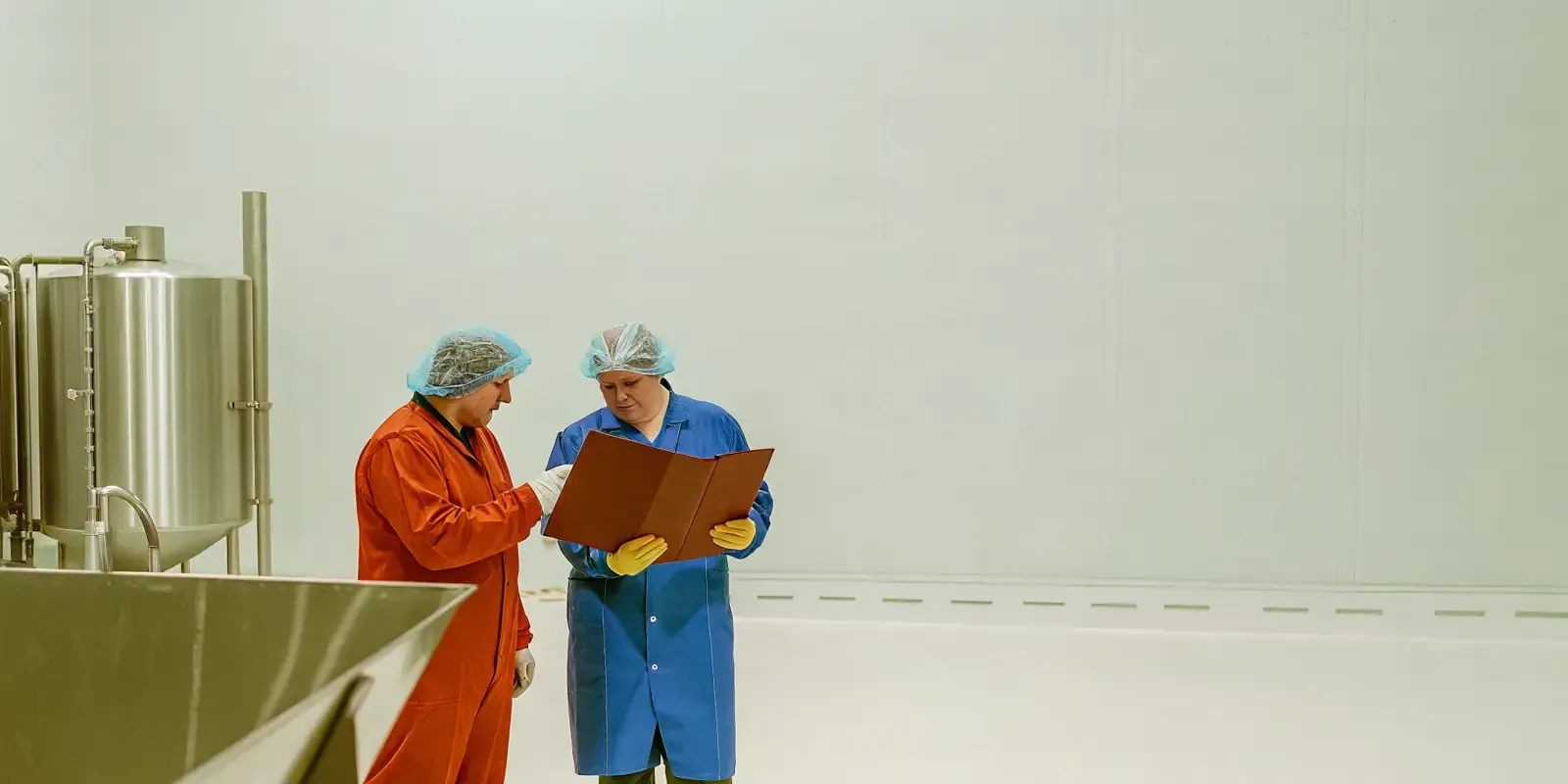 Food manufacturing facility quality assurance team reviewing production documents on the plant floor