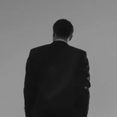 Man in a suit standing on railroad tracks, watching the sunrise.