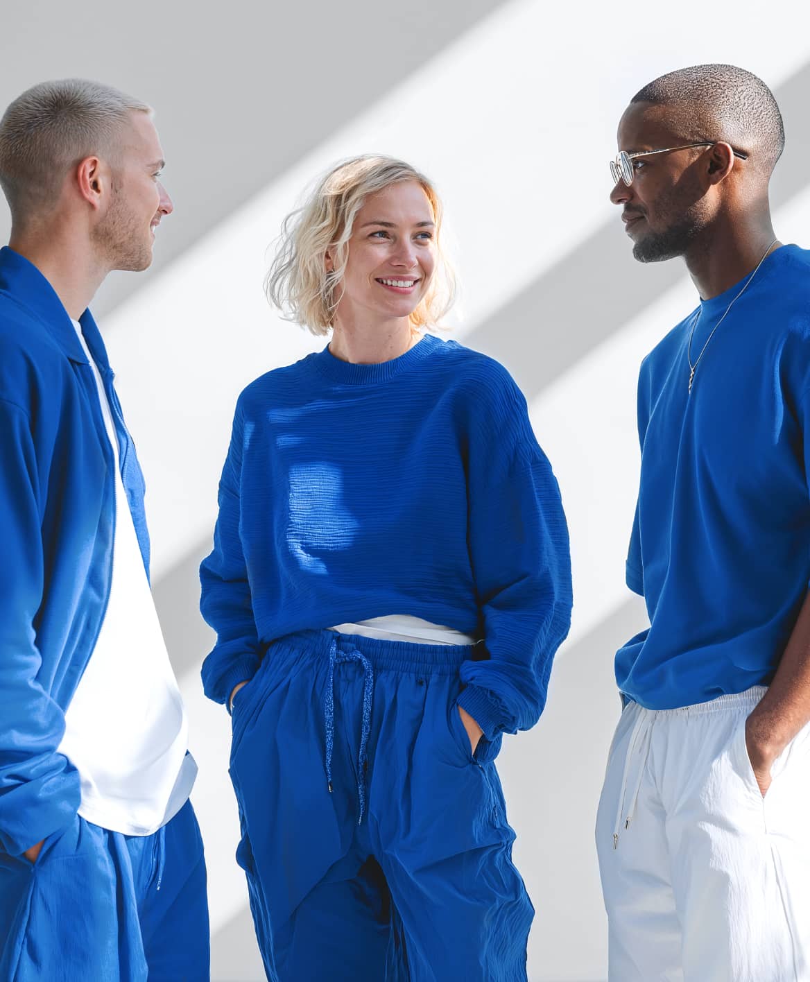 Three Friends Wearing Blue Athleisure Smiling In Bright Studio - Wealthflow Webflow Template | BRIX Template