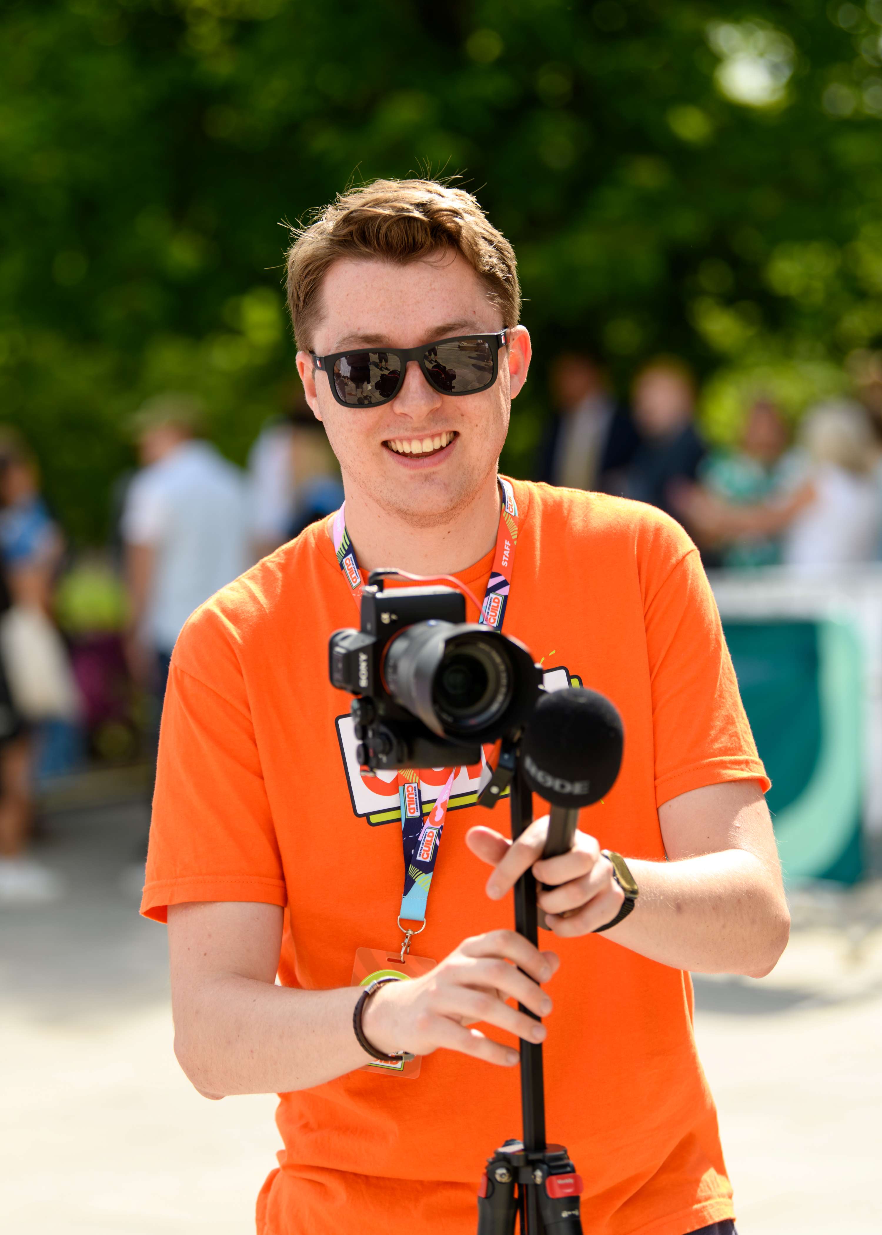Student in an orange top holding a camera